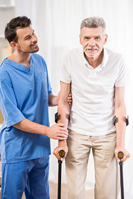white man in bright blue scrubs helping an eldering man walk with canes